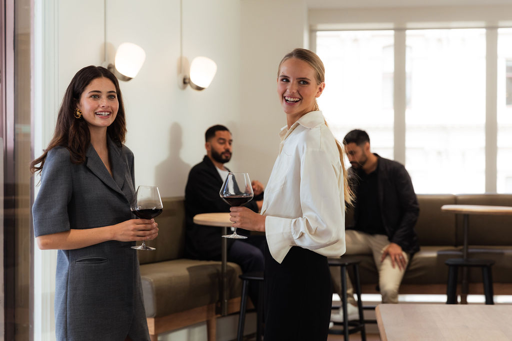 Two business women looking at camera while smiling in the lobby of the Alberts workspace