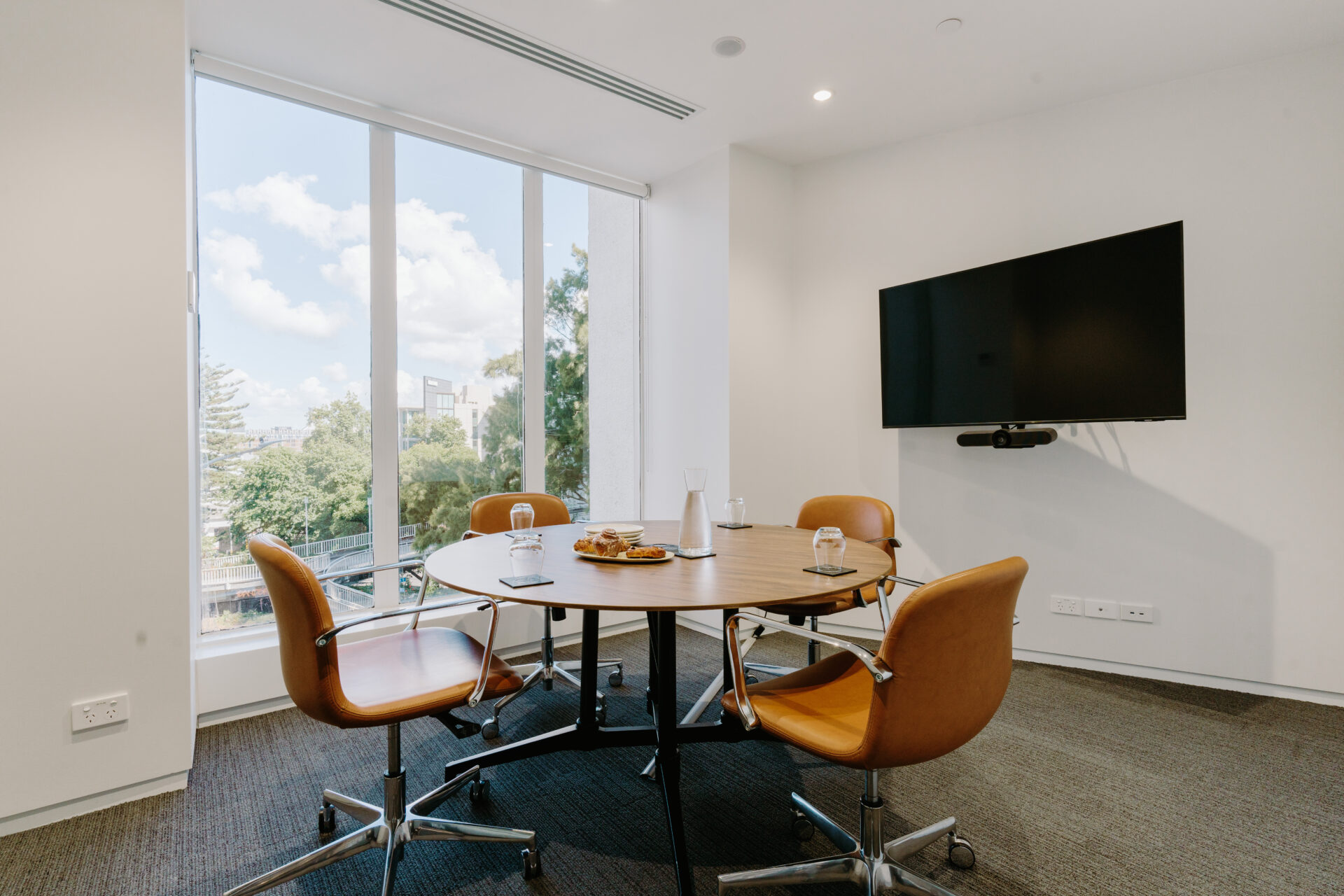 meeting rooms with round table, four chairs, and a screen